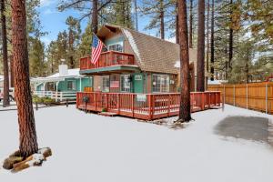 a house in the snow with an american flag at Tinker Bell Gambrel by Big Bear Vacations Ultra Relaxing Bear City Retreat in Big Bear City