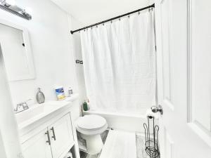 a white bathroom with a toilet and a sink at Peaceful home equal to a sound sleep! in Mastic Beach