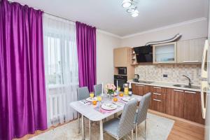 a kitchen with purple curtains and a table with chairs at Просторная 1ком квартира у Набережной Астаны in Astana