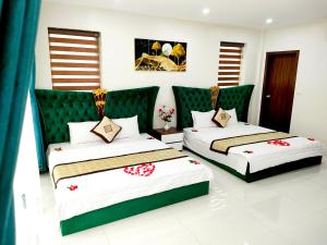 a bedroom with two beds and a green headboard at Villa FLC Sam Son Lavender in Sầm Sơn