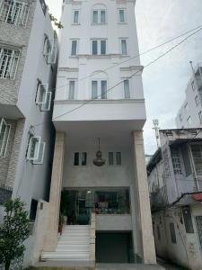 ein hohes weißes Gebäude mit einer Treppe davor in der Unterkunft MơMơ Residence in Ho-Chi-Minh-Stadt