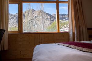 a bedroom with a window with a view of a mountain at Laksdup Guest House in Leh