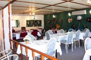 un comedor con mesas y sillas blancas en Colonial Inn Motel en Tamworth