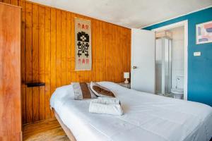 duże białe łóżko w pokoju z drewnianymi ścianami w obiekcie Casa Altavista w mieście Valparaíso