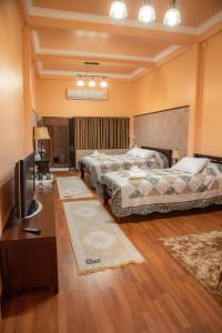 2 Betten in einem Zimmer mit einem TV und einem Zimmer mit Teppichen in der Unterkunft บ้านกิจเสรี 