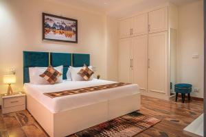 Schlafzimmer mit einem großen weißen Bett mit blauem Kopfteil in der Unterkunft Mystic Hill Crest Luxurious 2 BHK Apartments in Kasauli