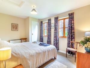 a bedroom with a bed and two windows at Water Hall Cottage in Chelsworth