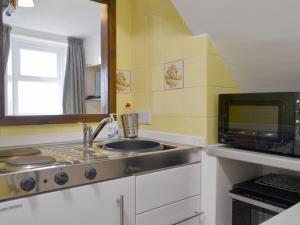 uma cozinha com um lavatório e um micro-ondas em Cosy Cottage em Allonby