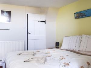 um quarto com uma cama branca com roupas em Cosy Cottage em Allonby