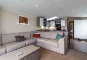 a living room with a couch and a kitchen at Luxury Caravan Boasting Full Sea Views At Hopton Holiday Park Ref 80041s in Great Yarmouth