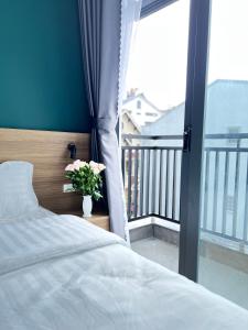 1 Schlafzimmer mit einem Bett und einem Balkon mit einer Blumenvase in der Unterkunft Su Apartment in Da Lat