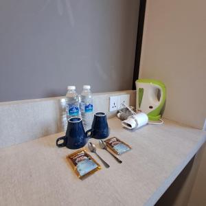 una encimera con botellas de agua y utensilios de cocina en C Hotel, en Jitra