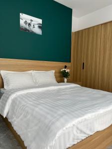 ein Schlafzimmer mit einem großen weißen Bett und einer grünen Wand in der Unterkunft Su Apartment in Da Lat