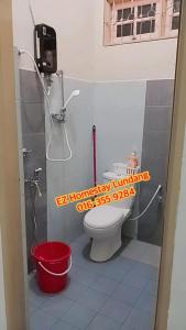 ein Badezimmer mit einem WC und einem roten Eimer in der Unterkunft EZ Homestay Lundang Kota Bharu in Kota Bharu