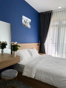 ein Schlafzimmer mit einem großen Bett mit blauer Wand in der Unterkunft Su Apartment in Da Lat