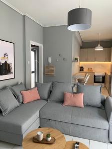 sala de estar con sofá gris y almohadas rosas en White elephant second floor apartment, en Volos