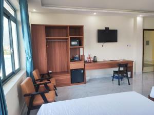 a room with a bed and a desk and a tv at Hoàng Anh Côn Đảo Hotel in Con Dao