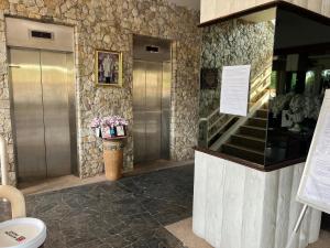 un vestíbulo con 2 ascensores y una escalera con flores en sea sand sun resort Executive Mae Rumphueng beach en Rayong