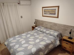 1 dormitorio con cama con colcha gris en Departamento amoblado Rio Cuarto en Río Cuarto
