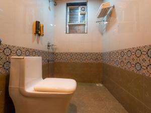 a bathroom with a toilet and a phone on the wall at Red Button Resort in Mahabaleshwar