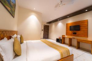 a bedroom with a large bed and a flat screen tv at Red Button Resort in Mahabaleshwar