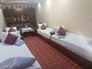 Habitación con 2 camas y alfombra roja. en Umarxon, en Bukhara