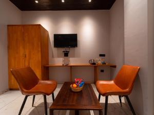 a room with two chairs and a table and a tv at Red Button Resort in Mahabaleshwar