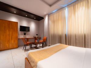 a bedroom with a bed and a desk and a television at Red Button Resort in Mahabaleshwar