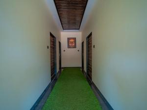 a corridor with white walls and a green carpeted hallway at Red Button Resort in Mahabaleshwar