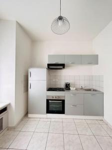 a white kitchen with a stove and a sink at Faubourg de Montbé in Montbéliard