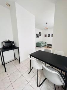 ein Esszimmer mit einem schwarzen Tisch und weißen Stühlen in der Unterkunft Faubourg de Montbé in Montbéliard