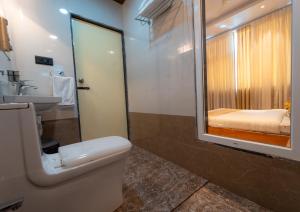 a bathroom with a toilet and a sink and a mirror at Red Button Resort in Mahabaleshwar