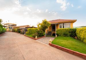 a house with a driveway in front of a yard at Red Button Resort in Mahabaleshwar