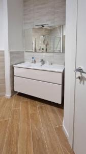 ein Badezimmer mit einem weißen Waschbecken und Holzböden in der Unterkunft Vignola New Apartment in Rom