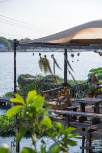 a group of tables and chairs next to a body of water at Baan GoLite Ko Kret - บ้านโกไล้เกาะเกร็ด in Nonthaburi