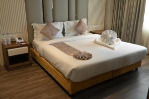 a bedroom with a bed with white sheets and pillows at Hotel Apricia in Ludhiana