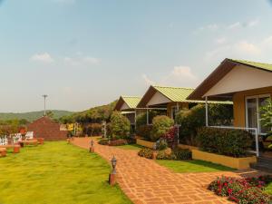 a row of houses in a yard with grass and flowers at Red Button Resort in Mahabaleshwar