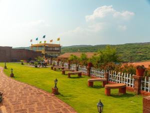 a row of benches in a field with a fence at Red Button Resort in Mahabaleshwar