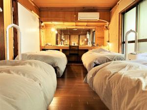 a room with three beds in it with a sink at 奄美ゲストハウス HUB a nice INN in Setouchi