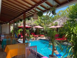 un patio con piscina, mesas y sombrillas en Molah Gili Villa, en Gili Air