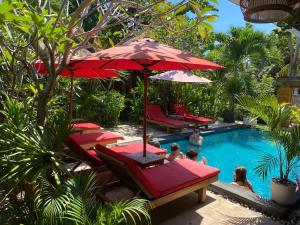 a pool with red chairs and umbrellas and people in it at Molah Gili Villa in Gili Air