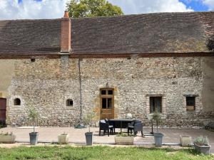 a stone building with a table in front of it at Domaine de Bisseret : Gîte pour golf et détente au cœur de la France - FR-1-489-438 in Lavault-Sainte-Anne