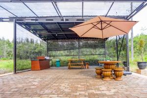 een patio met 2 tafels en een parasol bij SPOT ON 92523 Homestay Pasir Padi Permai Syariah in Pangkalpinang