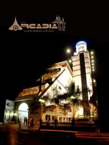 un edificio con una torre de reloj por la noche en Hotel Arcadia, en Kottayam