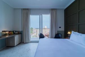 ポンディシェリにあるDe Fleur Hotelの大きなベッドと大きな窓のある寝室