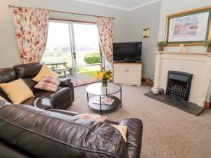 uma sala de estar com um sofá de couro e uma lareira em Forge Cottage em Morpeth