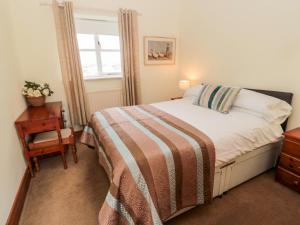 um quarto com uma cama, uma mesa e uma janela em Forge Cottage em Morpeth