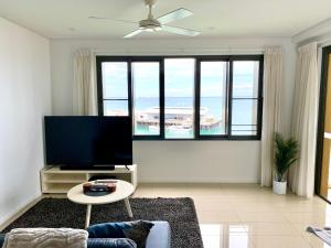 a living room with a flat screen tv and a table at Absolute Waterfront - Tropical Oasis Over The Water in Darwin