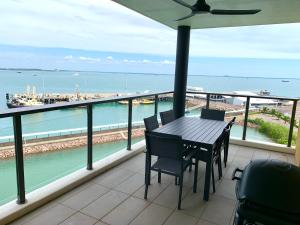 a table and chairs on a balcony with a view of the ocean at Absolute Waterfront - Tropical Oasis Over The Water in Darwin