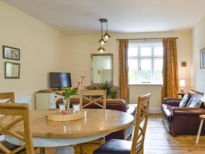a living room with a dining room table and a couch at Upper Broughton Farm Cottage in Snead